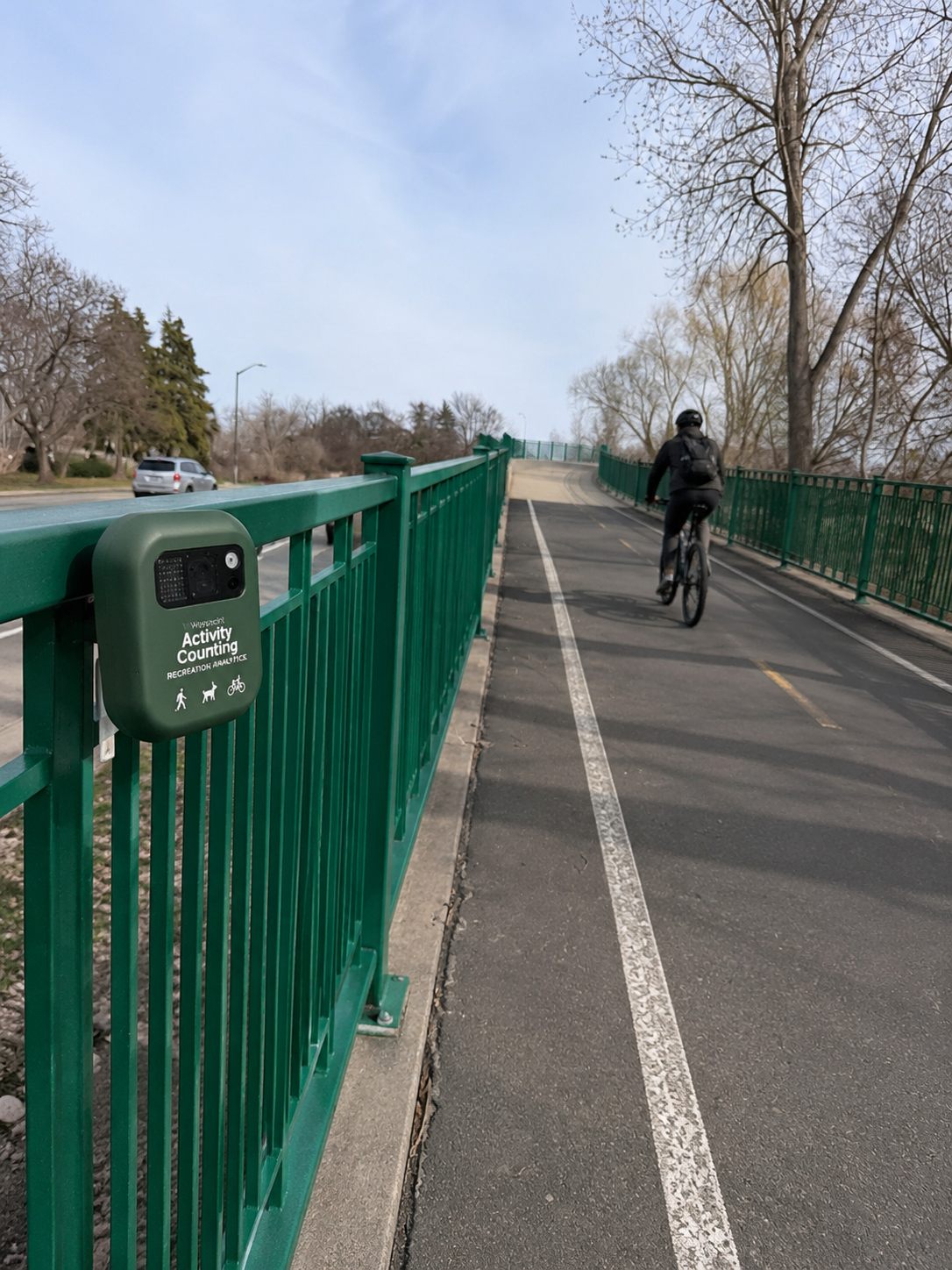 Waypoint camera on a shared-use path railing as a cyclist passes